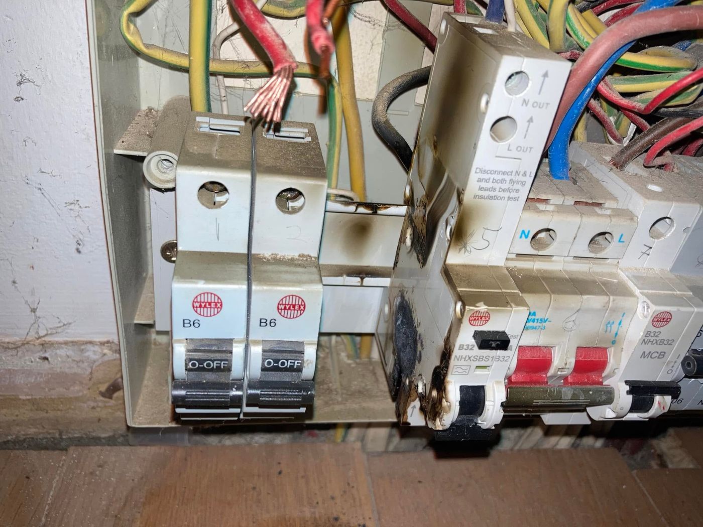 Fire-damaged circuit breakers in an old fuse board